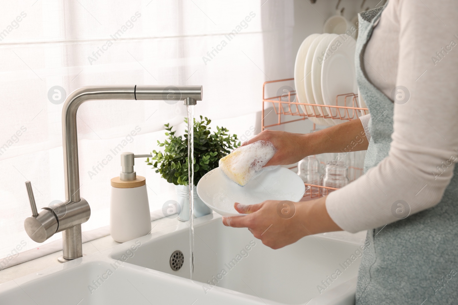 Photo of Woman washing bowl at sink in kitchen, closeup