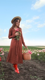 Woman with basket of roses in beautiful blooming field