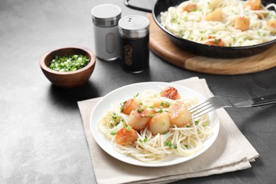 Delicious scallop pasta with green onion served on grey table