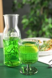 Photo of Delicious drink with tarragon in glass on green table. Space for text