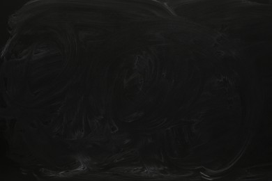 Photo of Chalk rubbed out on black chalkboard as background, closeup. Space for text