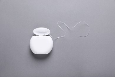 Container with dental floss on grey background, top view. Space for text