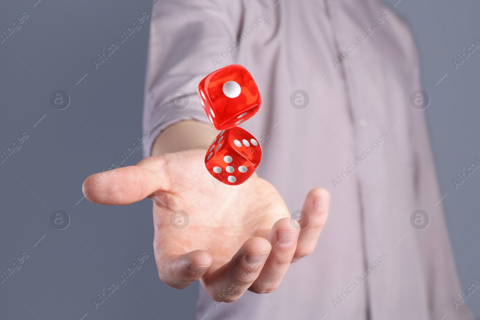 Image of Man throwing red dice on grey background, closeup