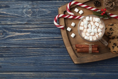 Hot drink with marshmallows and sweets on blue wooden table, top view. Space for text