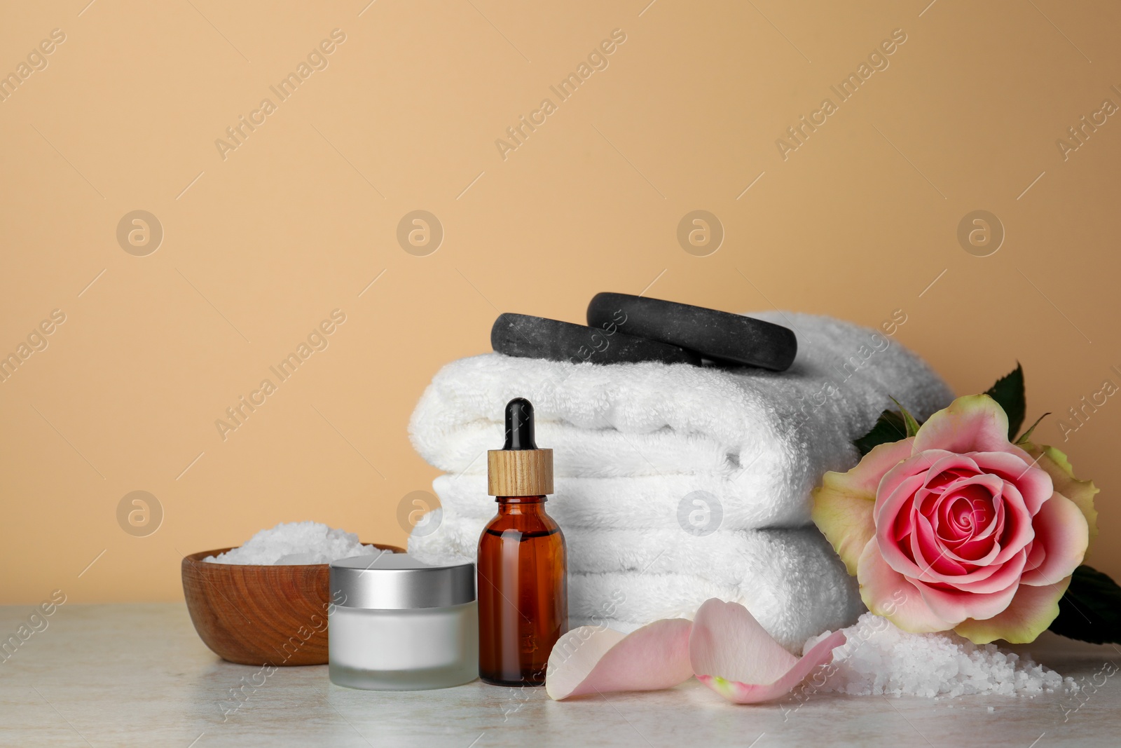 Photo of Composition with different spa products and rose on beige table. Space for text