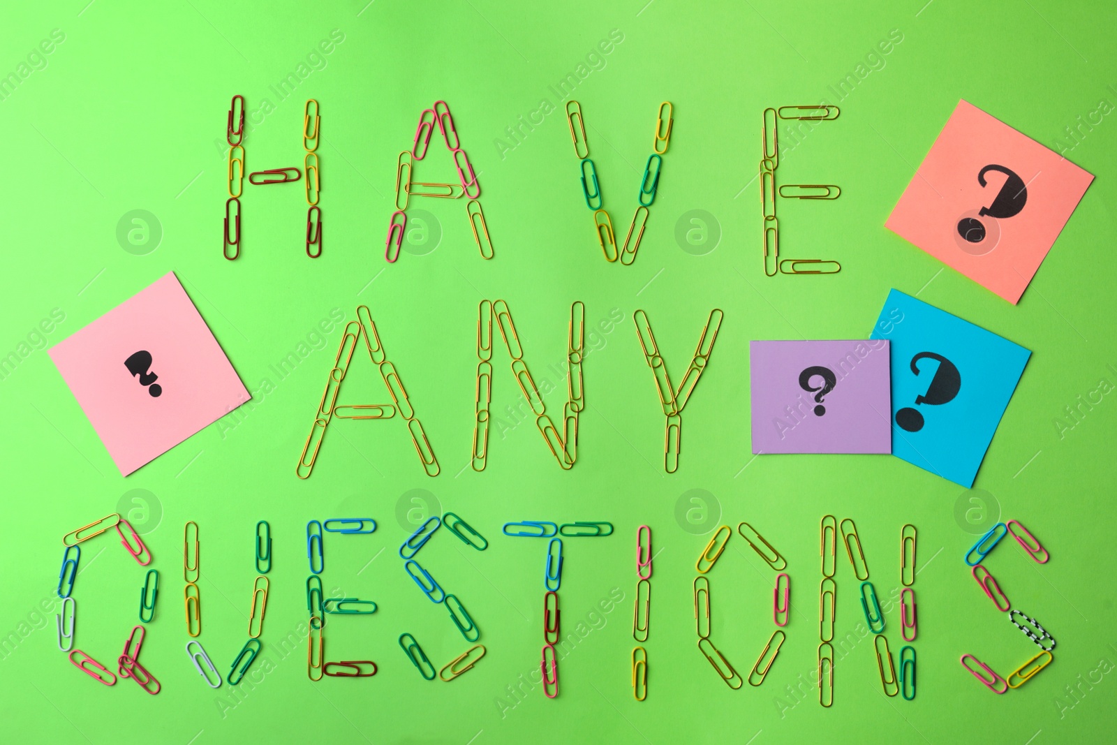 Photo of Phrase HAVE ANY QUESTIONS with paperclips and query marks on green background, flat lay