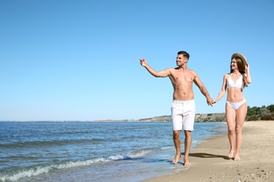 Woman in bikini and her boyfriend on beach, space for text. Happy couple