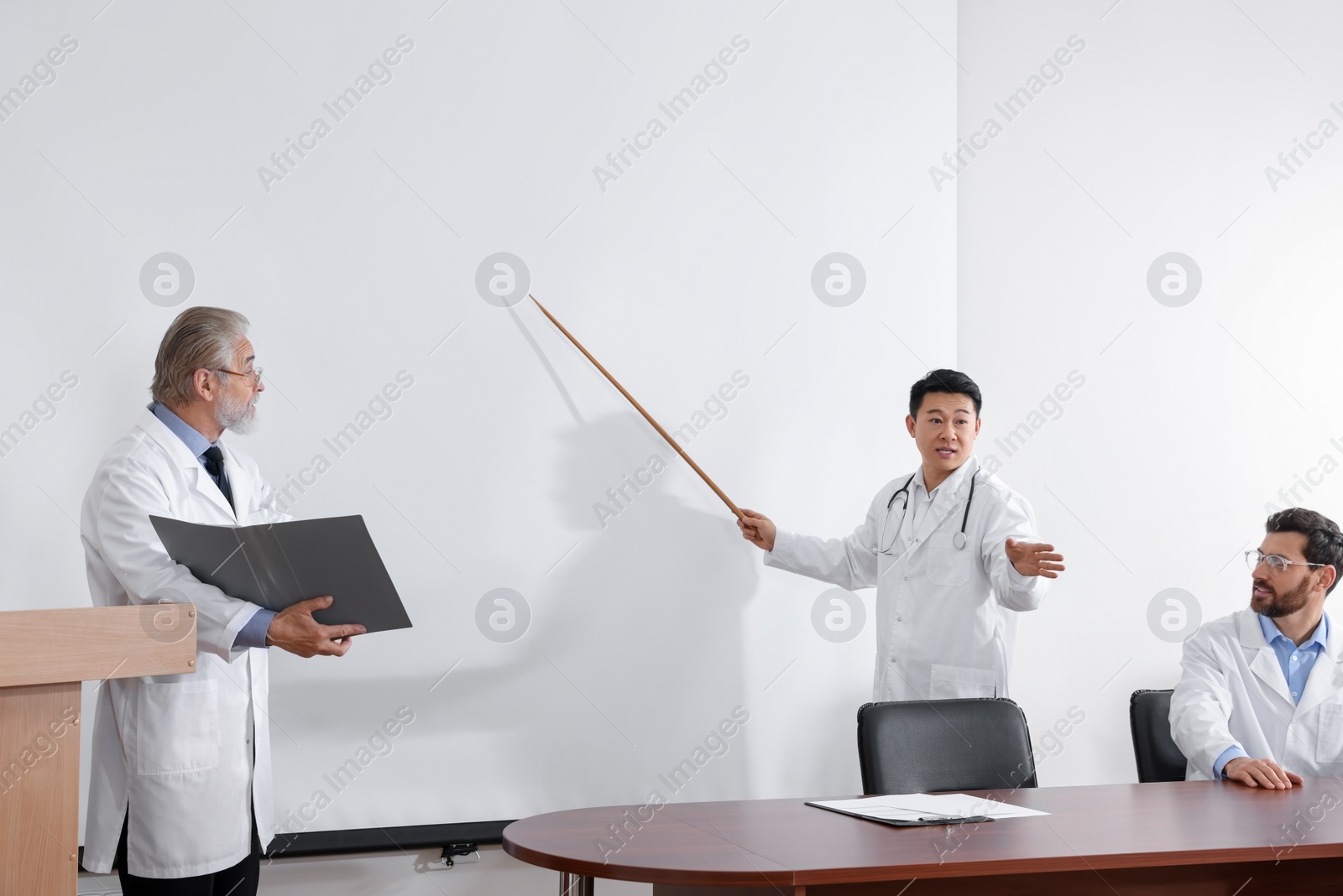 Photo of Doctors giving lecture near projection screen in conference room