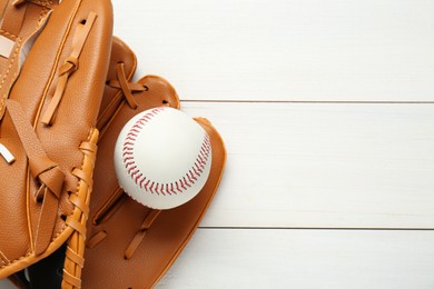 Photo of Leather baseball glove with ball on white wooden table, top view. Space for text