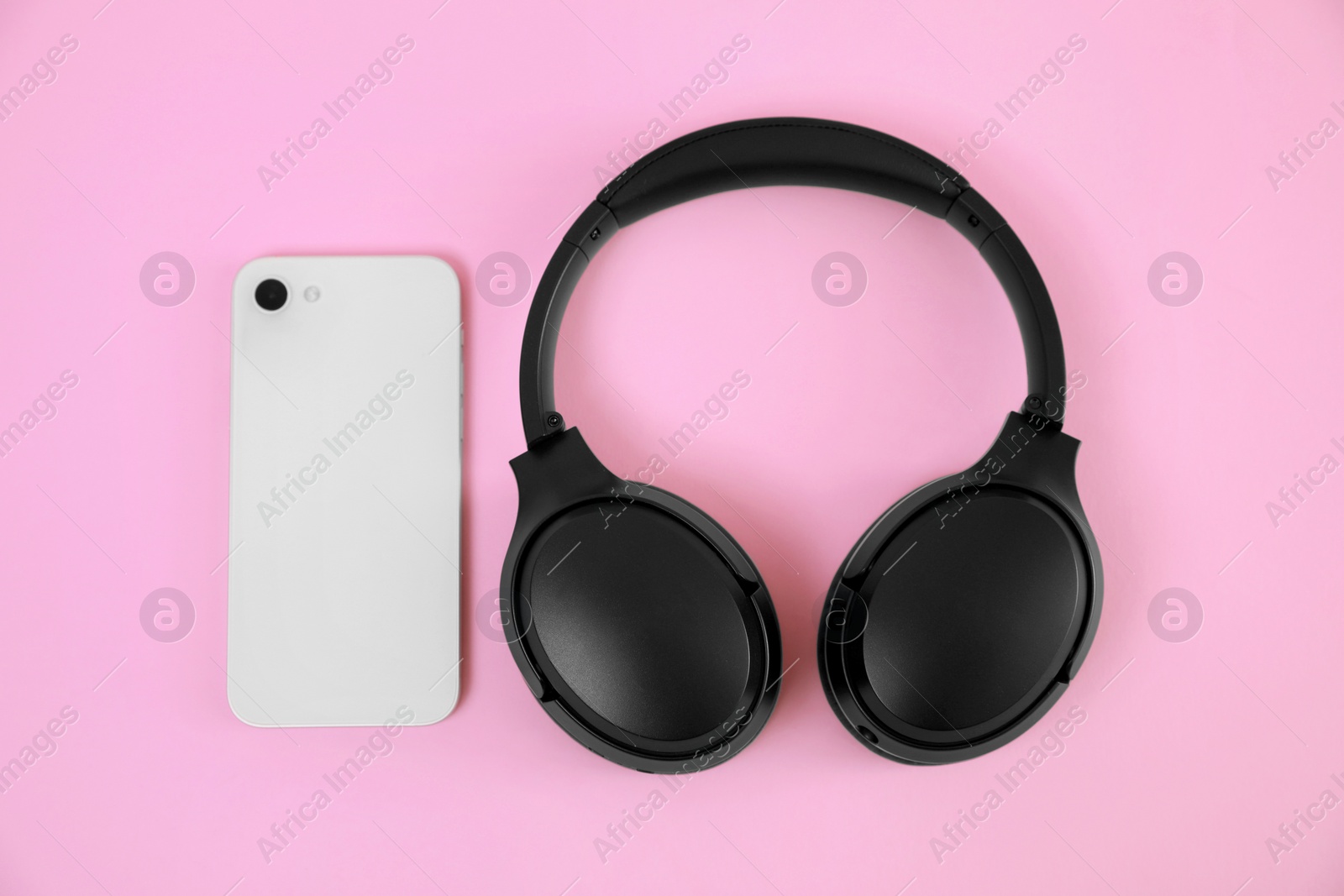 Photo of Modern wireless headphones and smartphone on pink background, flat lay