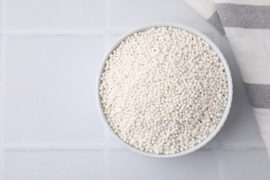 Photo of Tapioca pearls in bowl on white tiled table, top view. Space for text