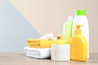 Photo of Baby cosmetic products, toy and towels on table against color background. Space for text