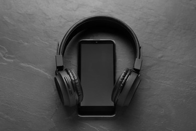 Photo of Smartphone with blank screen and headphones on grey textured background, top view with space for text. Sound equipment