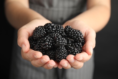 Photo of Young woman with handful of ripe blackberries, closeup