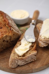 Tasty bread with butter and knife on white table, closeup. Space for text