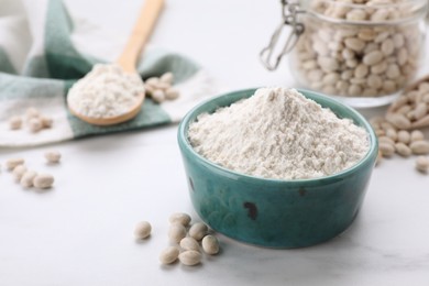 Photo of Bean flour and seeds on white marble table. Space for text