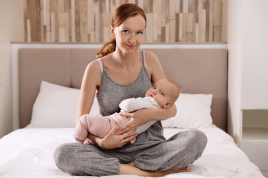 Photo of Young woman with her little baby resting after breast feeding in bedroom