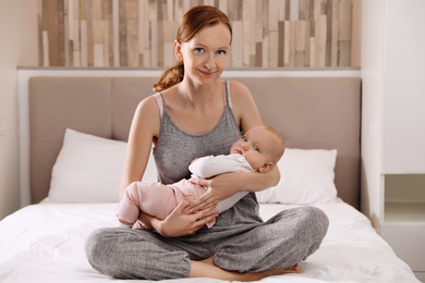 Young woman with her little baby resting after breast feeding in bedroom