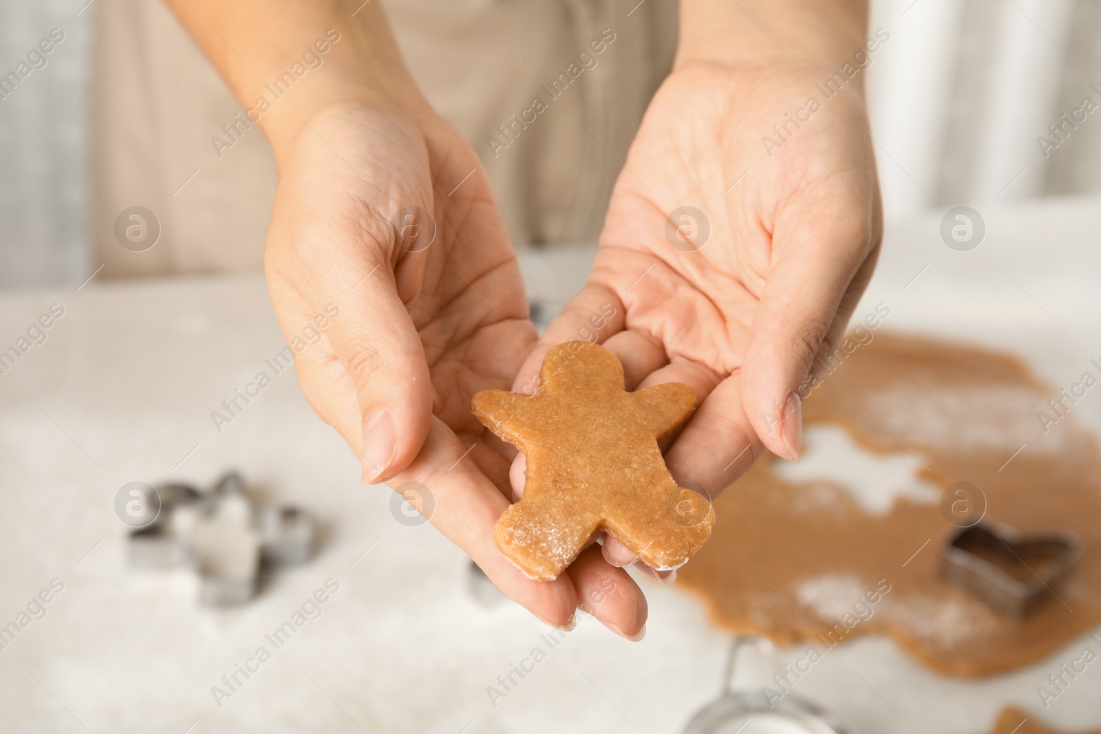 Photo of Woman holding Christmas cookie at light table, closeup