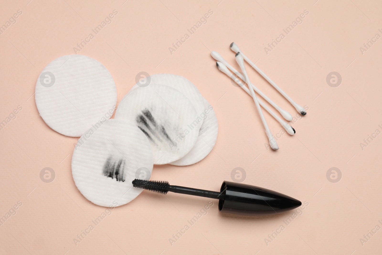 Photo of Dirty cotton pads after removing makeup, applicator brush and swabs on beige background, flat lay
