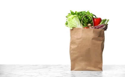 Photo of Paper bag with vegetables on table against white background. Space for text