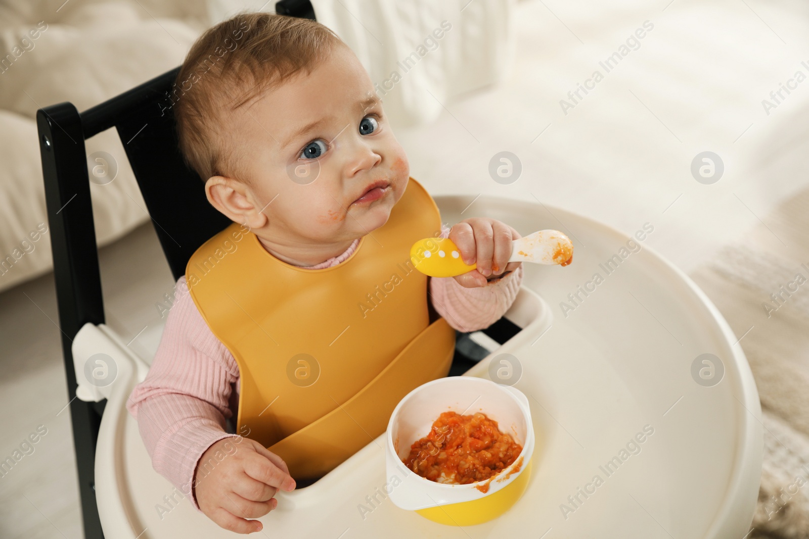 Photo of Cute little baby wearing bib while eating at home