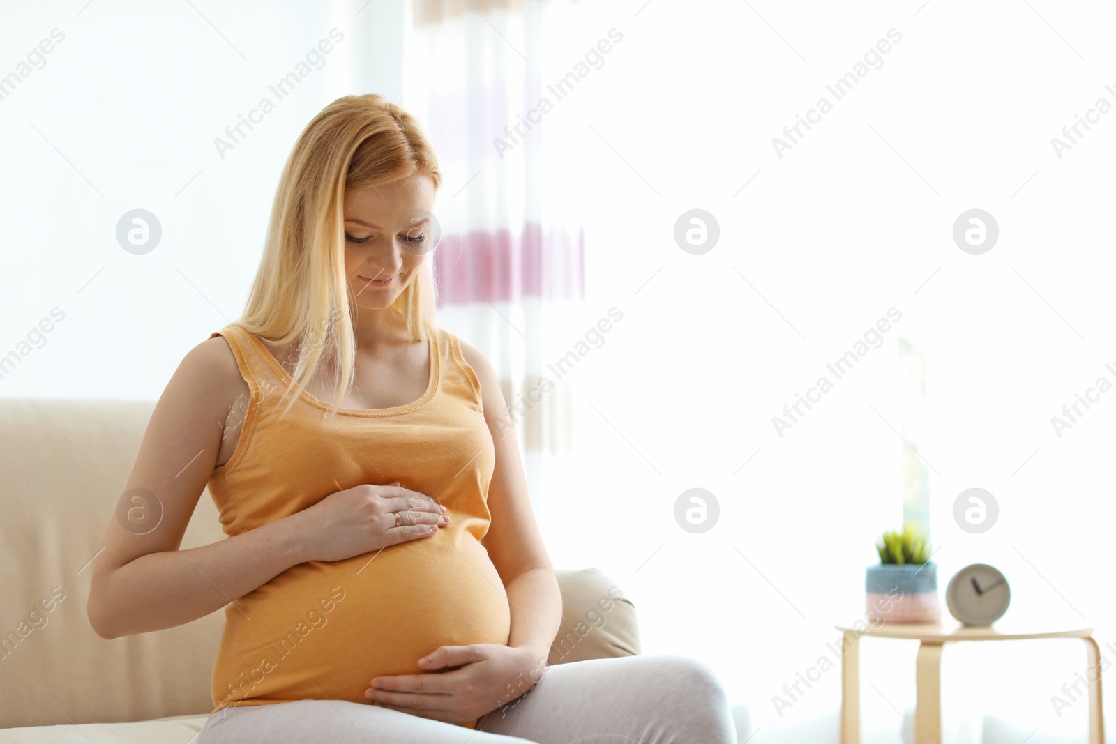 Photo of Beautiful pregnant woman sitting on sofa at home