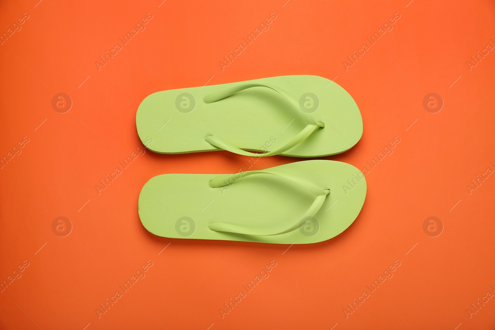 Photo of Stylish light green flip flops on orange background, top view