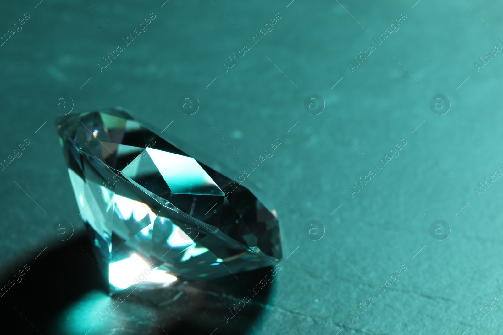 Photo of Beautiful dazzling diamond on green textured background, closeup. Space for text