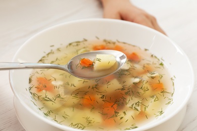 Sick woman eating fresh homemade soup to cure flu at table, closeup