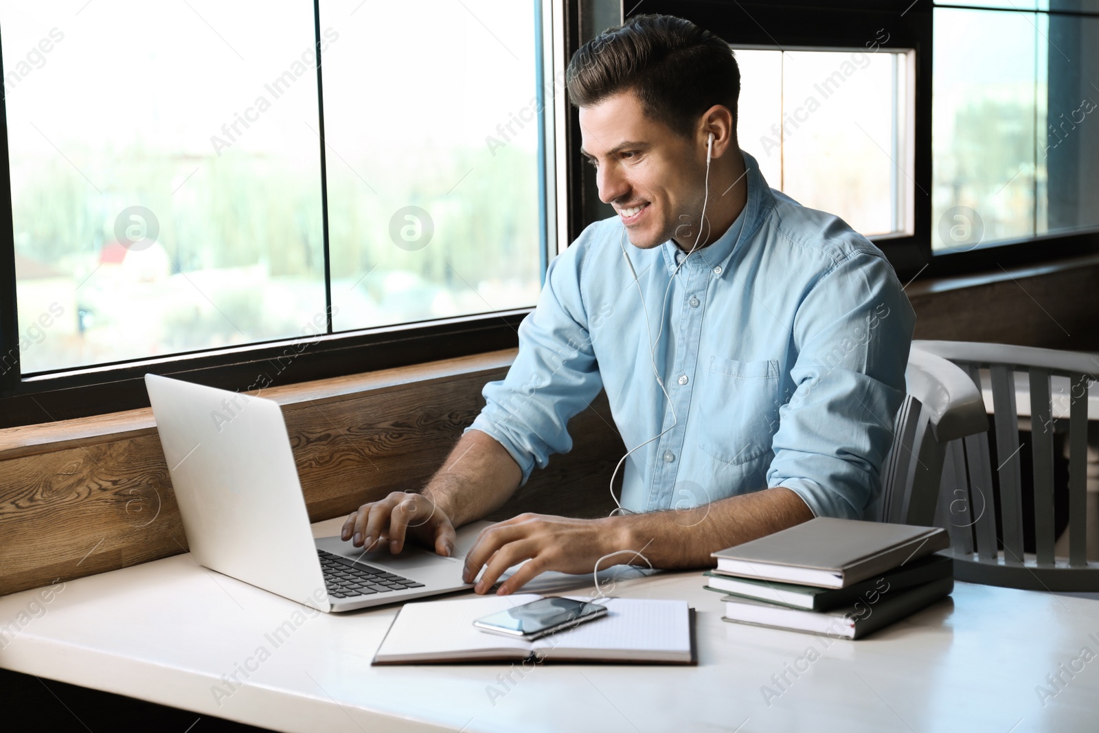 Photo of Man listening to audiobook at table in cafe