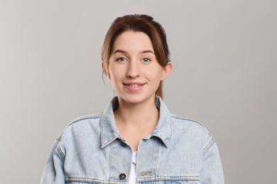 Portrait of smiling woman with dental braces on grey background