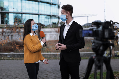 Young journalist and businessman with medical masks outdoors. Virus protection