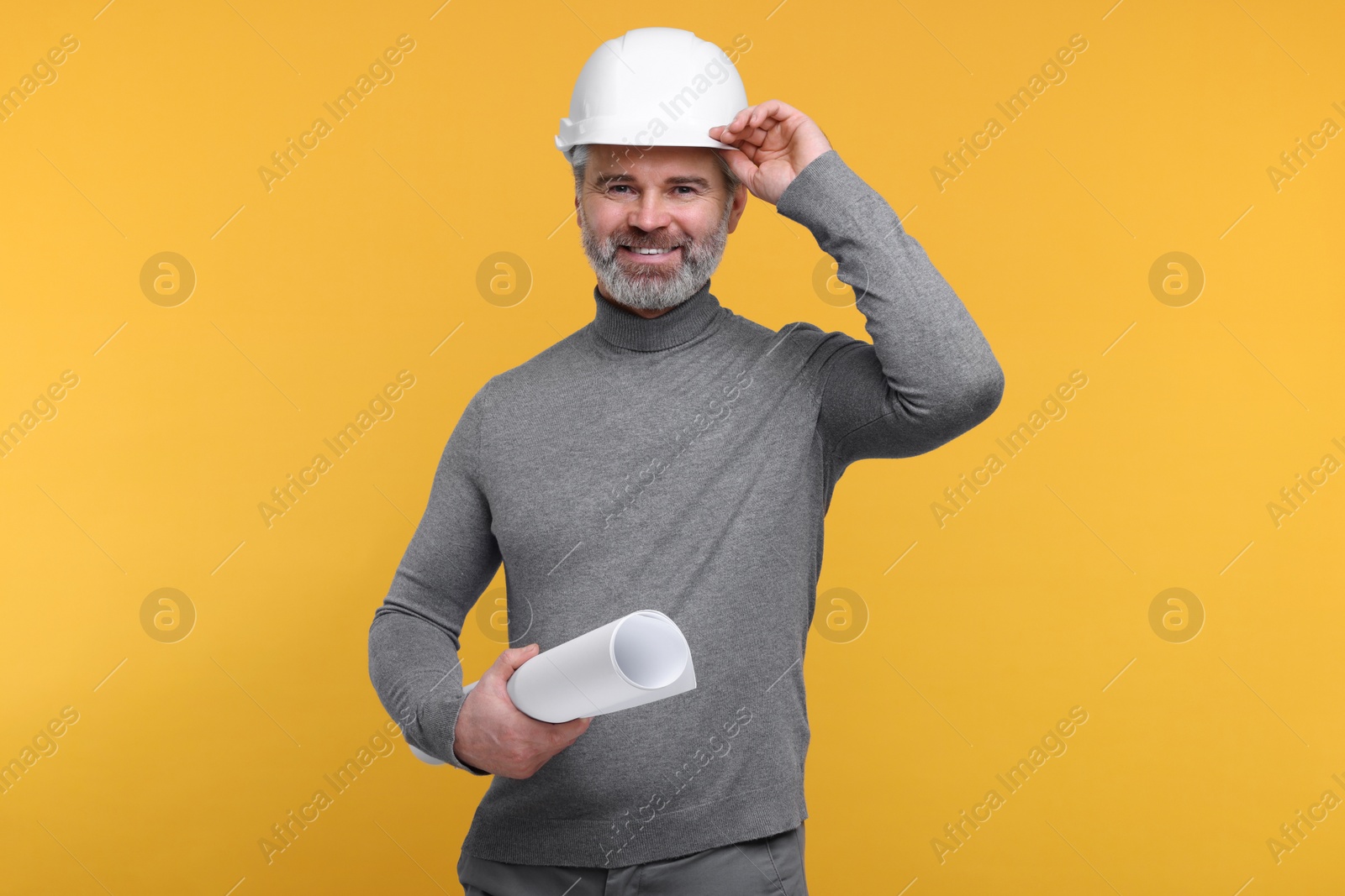 Photo of Architect in hard hat holding draft on orange background