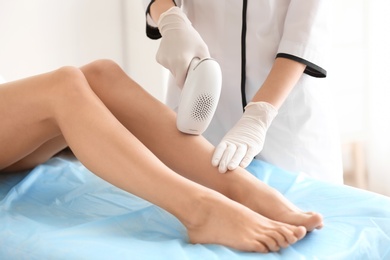 Woman undergoing hair removal procedure with photo epilator in salon