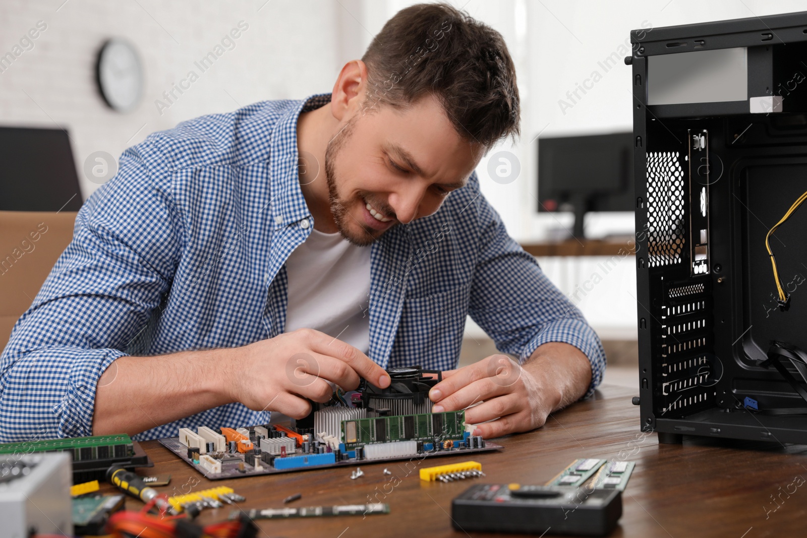 Photo of Male technician repairing motherboard at table indoors