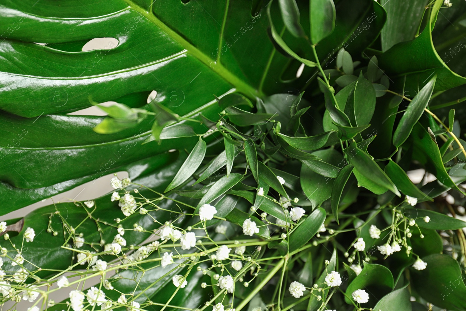 Photo of Beautiful bouquet with white flowers and green leaves, closeup. Floral background