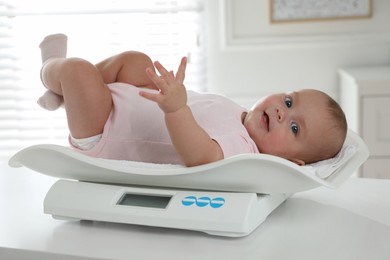 Photo of Cute little baby lying on scales at home