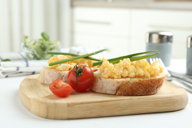Tasty scrambled egg sandwiches on white wooden table