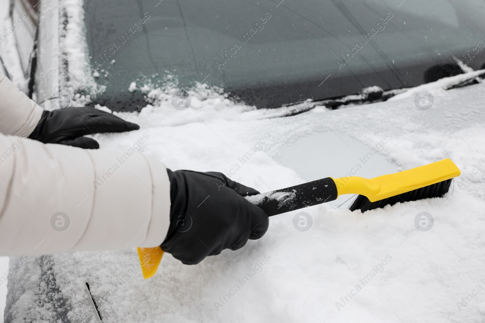 Photo of Man cleaning snow from car hood outdoors, closeup