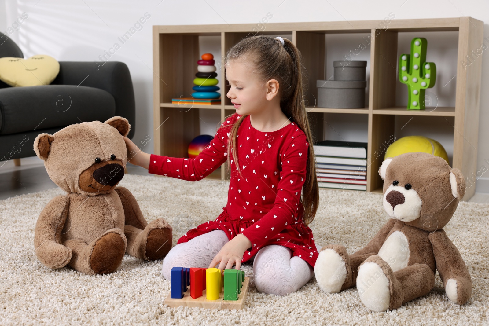 Photo of Cute little girl playing with teddy bears and cubes at home