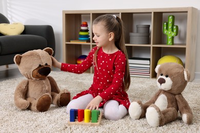 Photo of Cute little girl playing with teddy bears and cubes at home