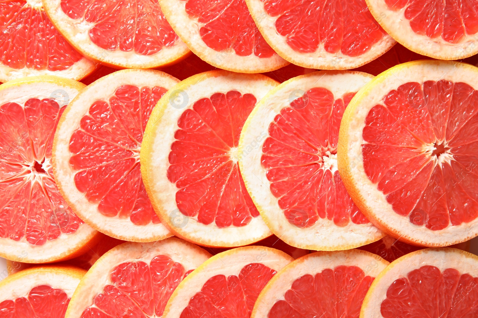 Photo of Many sliced fresh grapefruits as background, top view