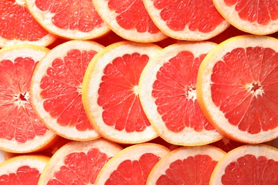 Many sliced fresh grapefruits as background, top view