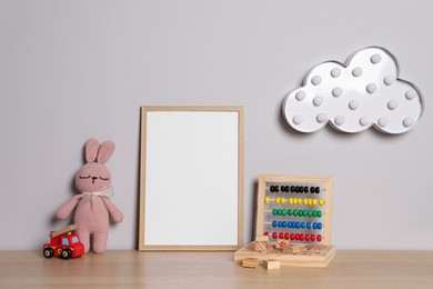 Photo of Empty square frame and different toys on wooden table
