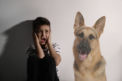 Image of Scared little boy suffering from cynophobia on white background. Irrational fear of dogs
