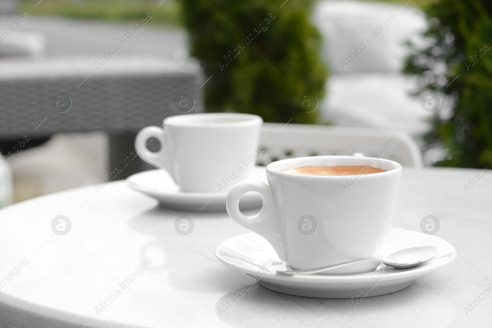 Photo of Ceramic cups of aromatic coffee with foam on table in morning