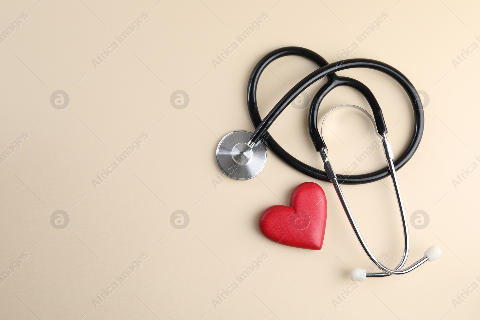 Photo of Stethoscope and red heart on beige background, top view. Space for text