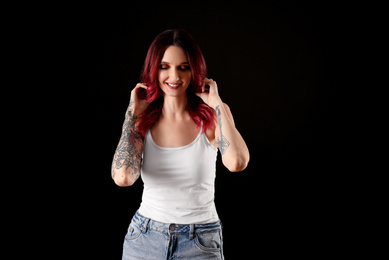 Photo of Beautiful woman with tattoos on arms against black background