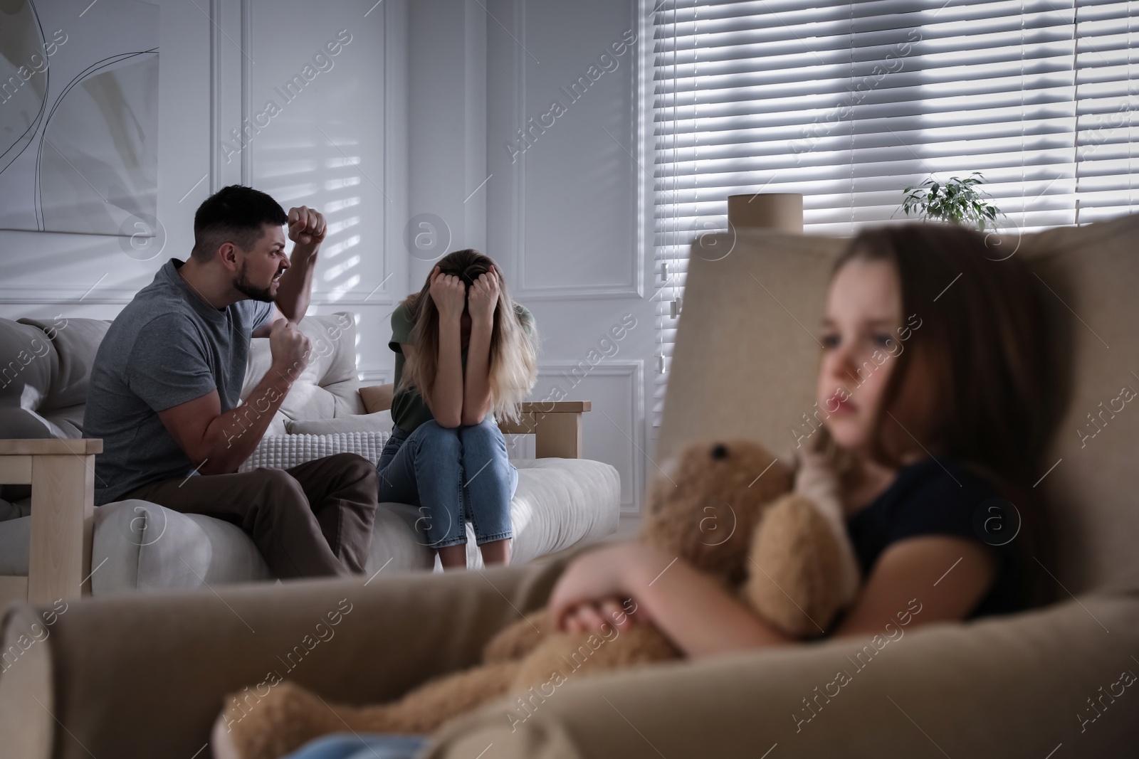 Photo of Couple fighting at home in presence of their little daughter. Domestic violence